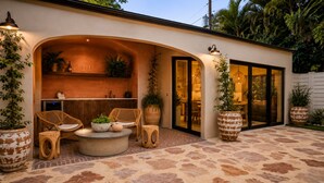 An outdoor patio area with a stone floor, wicker furniture, and large potted plants. - Vrbo Property (Miami)