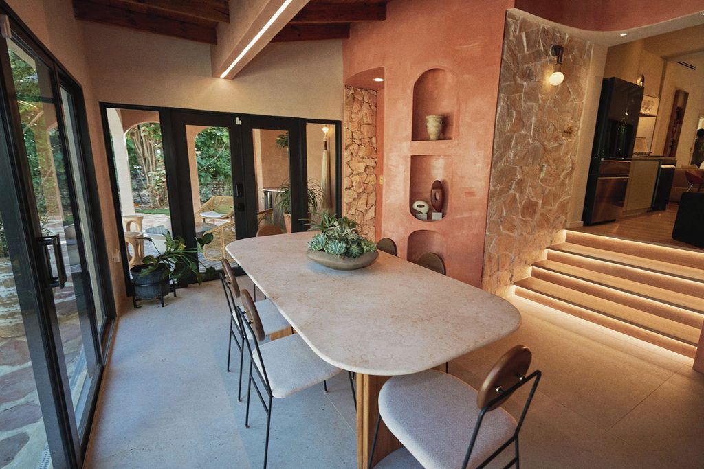 A modern kitchen with a stone accent wall, a dining area with a table and chairs, and a view of the outdoors.