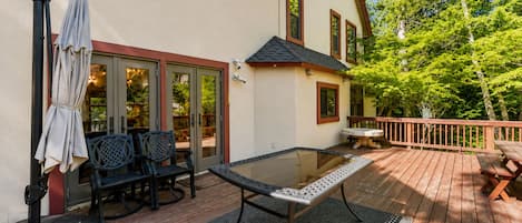 Une terrasse extérieure avec une table à plateau de verre, des chaises et un banc.