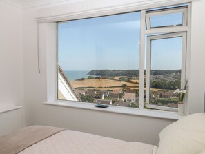 A bedroom with a large window overlooking a coastal landscape. - Elberry Cove View (Paignton)