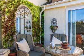 A patio with wicker chairs, a glass table, and potted plants. - Elberry Cove View (Paignton)