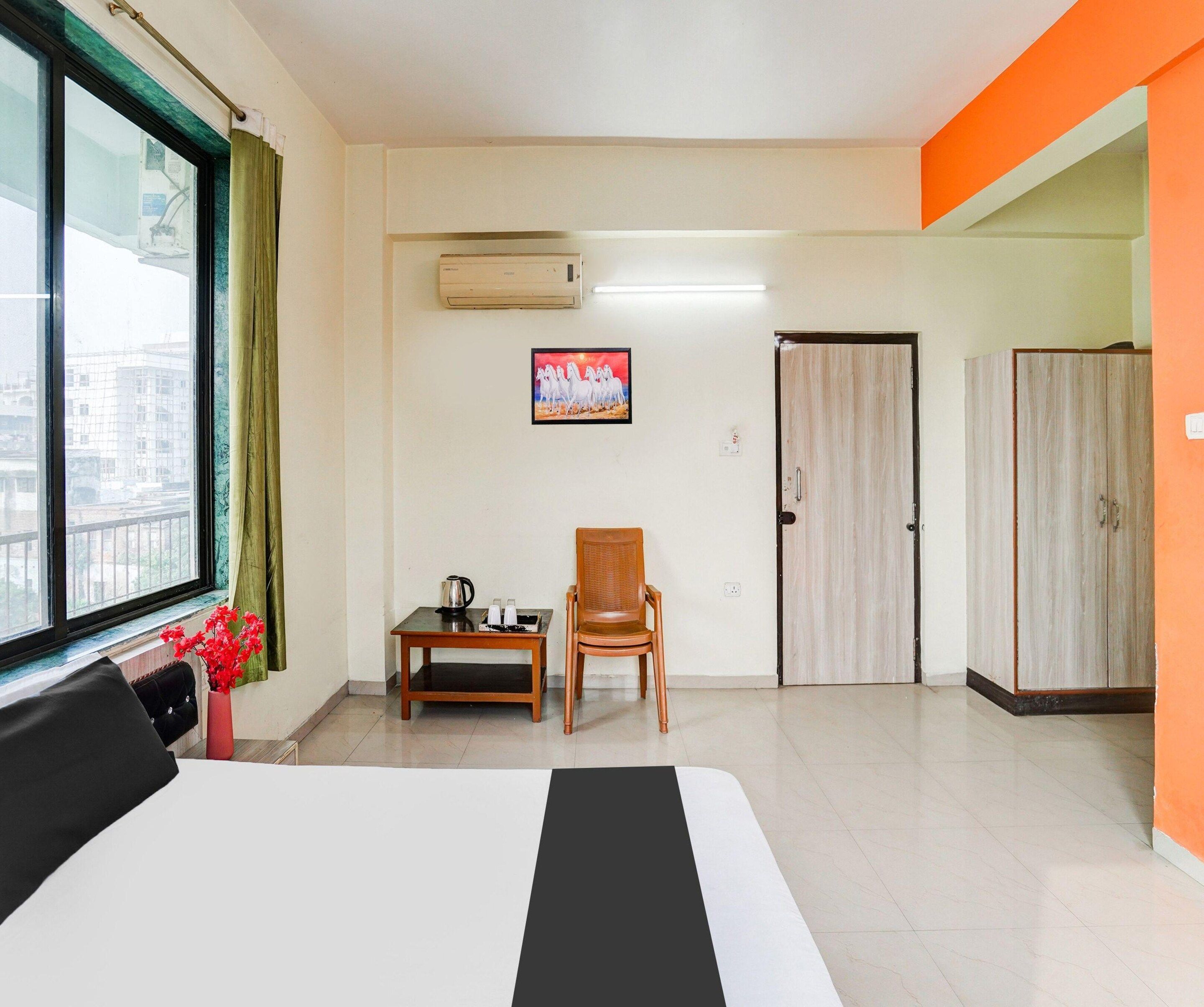 Habitación de hotel con cama, una silla, una mesita, aire acondicionado, un cuadro en la pared y un armario.