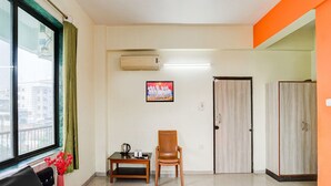A hotel room with a bed, a chair, a small table, an air conditioning unit, a picture on the wall, and a wardrobe. - Deluxe Khanka Chowk Darbhanga (Darbhanga)