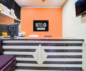 A hotel reception desk with a sign that reads 'HOTELO Company Serviced.'