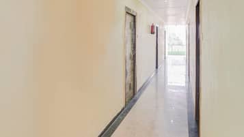 A long, narrow hallway with doors on both sides and a tiled floor.