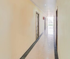 A long, narrow hallway with doors on both sides and a tiled floor.