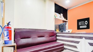A hotel room with a sofa, a small table, a fire extinguisher, and a sign indicating the room is company-serviced. - Deluxe Khanka Chowk Darbhanga (Darbhanga)