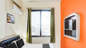 A hotel room with a bed, a window with curtains, an air conditioning unit, and a painting on the wall. - Deluxe Khanka Chowk Darbhanga (Darbhanga)