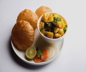 Un plato con dos bollos, un cuenco de puré de patatas, una rodaja de zanahoria y media lima.