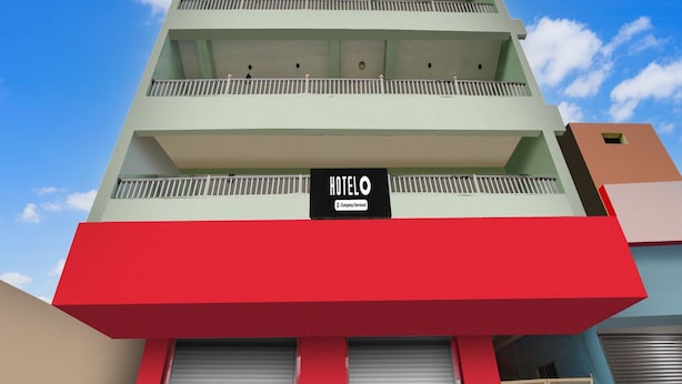 A hotel with a red and green facade, multiple balconies, and a sign indicating it is company-serviced. - Deluxe Khanka Chowk Darbhanga (Darbhanga)
