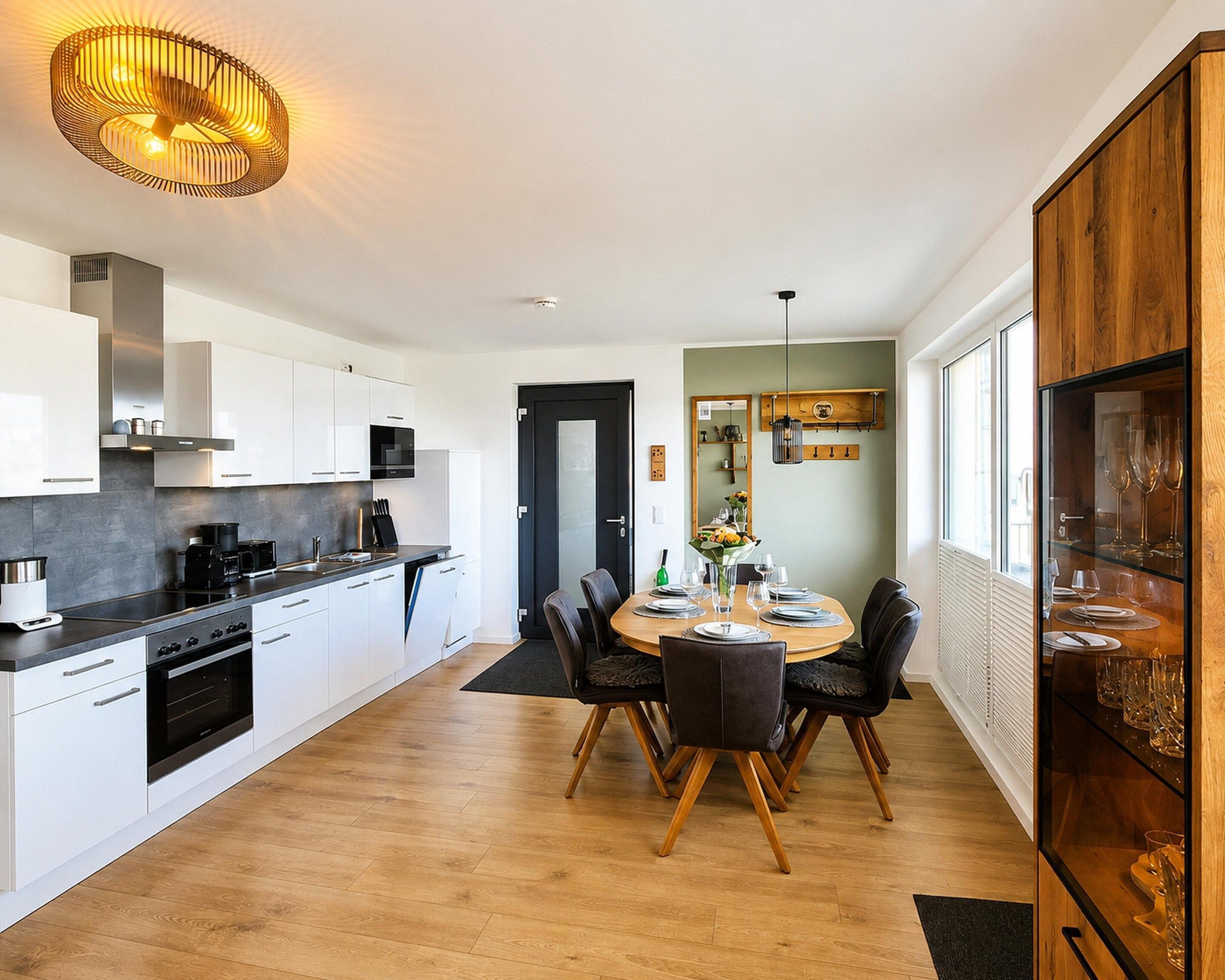 A modern kitchen with white cabinets, a black stove, and a dining area with a wooden table and chairs.