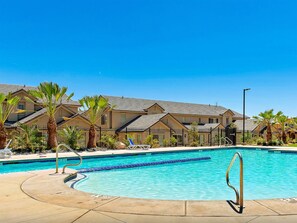 A swimming pool with a clear blue water, surrounded by a fence, palm trees, and a row of houses in the background. - Hot Tub, Heated Pool, Ping Pong, Foosball, xBox, FastWiFi in Southern Utah (Washington)