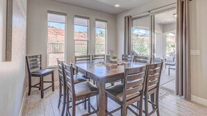 Un espace repas comprenant une grande table et des chaises, de grandes fenêtres et une vue sur l’extérieur.