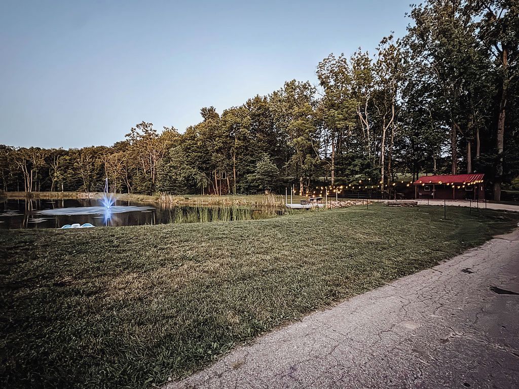 A park with a pond, a red-roofed structure, and a paved path.