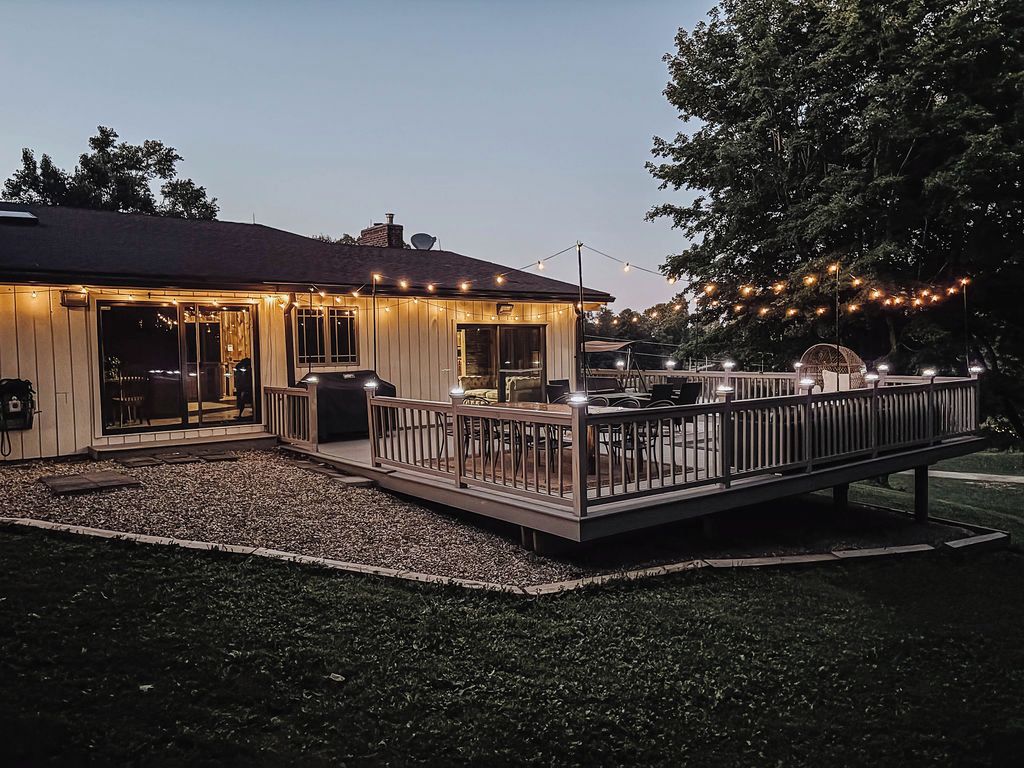Une maison avec une terrasse, des meubles d’extérieur et des guirlandes lumineuses.