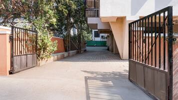 Un camino cerrado que lleva a un edificio, con un coche verde estacionado al fondo.