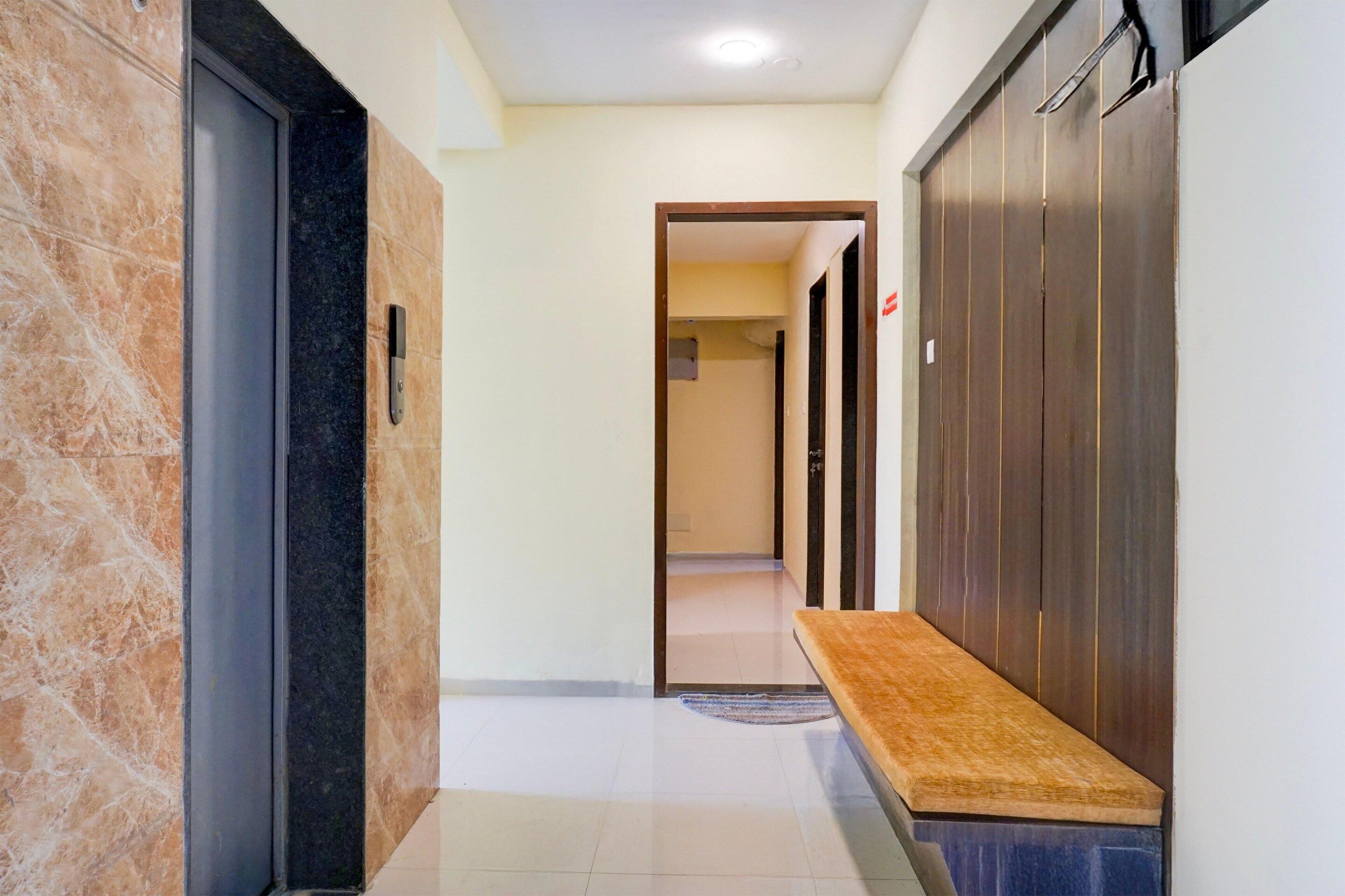 A hallway with a bench, a door with a handle, and a wall with a vertical stripe pattern.