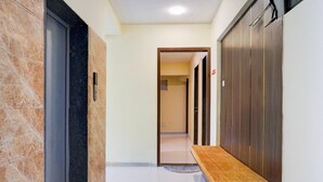 A hallway with a bench, a door with a handle, and a wall with a vertical stripe pattern. - Deluxe Zudio 7 Baner (Pune)