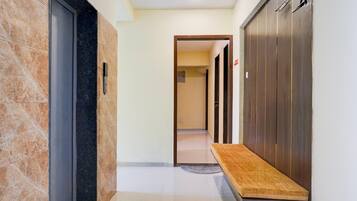 A hallway with a bench, a door with a handle, and a wall with a vertical stripe pattern.
