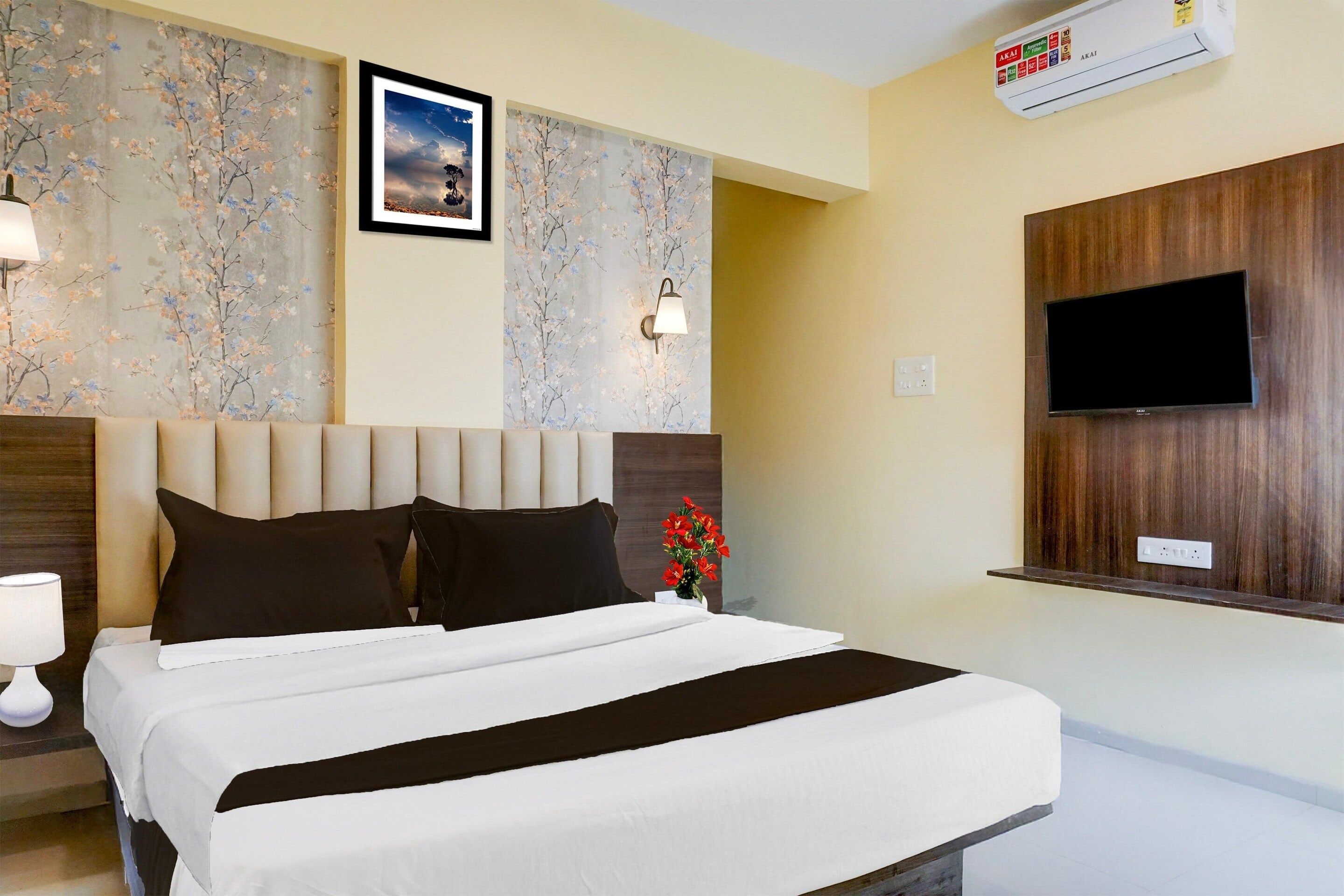 A hotel room with a bed, a wall-mounted TV, and a floral wallpaper.