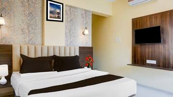 A hotel room with a bed, a wall-mounted TV, and a floral wallpaper.
