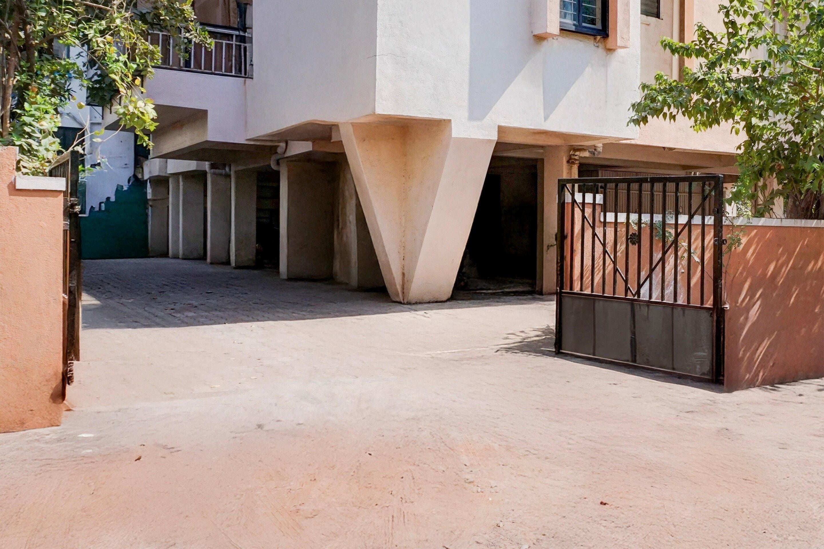 A building with a gated entrance, a concrete structure, and a staircase leading to an upper level.