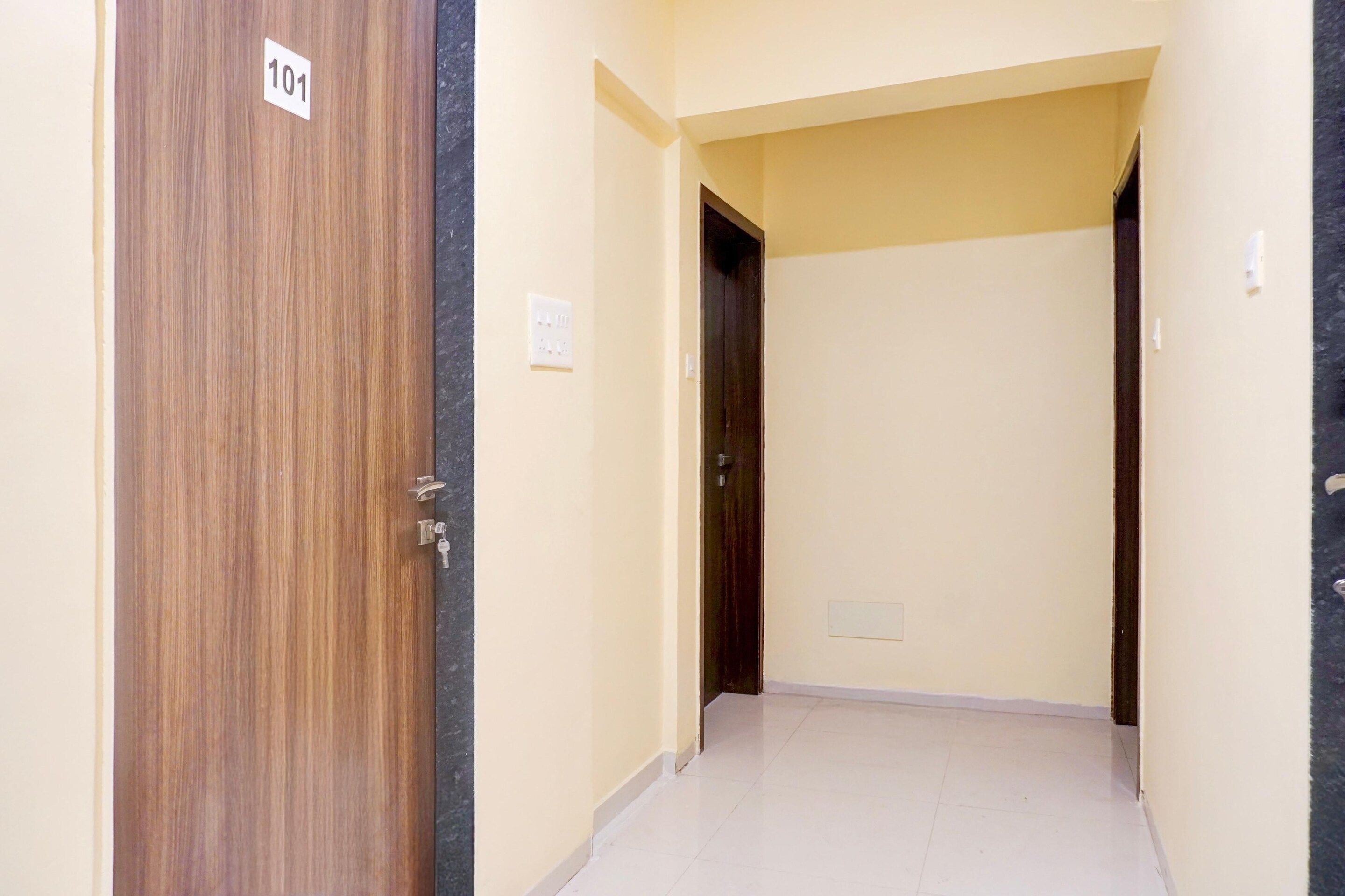 A hallway with a wooden door labeled '101' and a light switch on the wall.