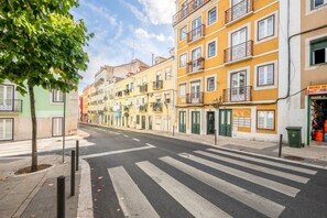 Eine Straße mit Gebäuden, einer Fußgängerampel und einem Baum.