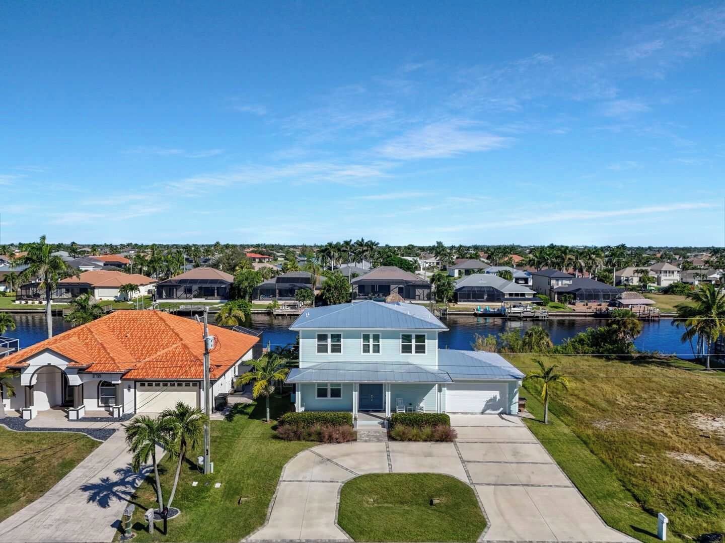 A residential area with houses, a body of water, and a clear sky.