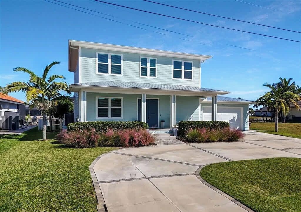 A two-story house with a front porch, a garage, and a well-maintained lawn.