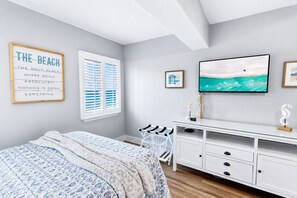 Ein Schlafzimmer mit einem Bett, einem Schreibtisch, einem Fernseher und einem Fenster mit Jalousien.
