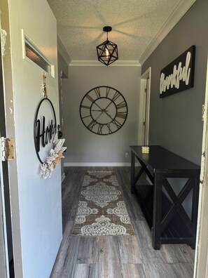 Un pasillo con un tapete decorativo, un reloj de pared y un banco.