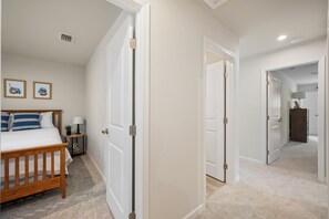 A bedroom with a bed, bedside tables, a nightstand, and a wall-mounted shelf. - Modern Family Retreat Near Liberty University (Lynchburg)