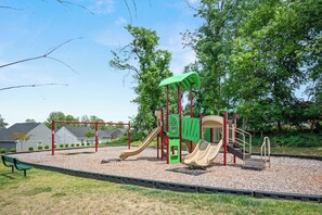 A playground with a slide and climbing structures, surrounded by trees and a grassy area. - Modern Family Retreat Near Liberty University (Lynchburg)