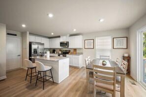 A modern kitchen with white cabinetry, a stainless steel refrigerator, and a built-in microwave. - Modern Family Retreat Near Liberty University (Lynchburg)