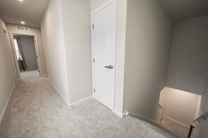 A hallway with carpeted flooring, white walls, and a closed white door. - Modern Family Retreat Near Liberty University (Lynchburg)
