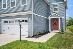 Un immeuble résidentiel de deux étages, doté d’un garage, d’une porte d’entrée rouge et d’une boîte aux lettres.
