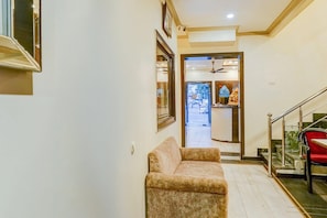 Un pasillo con un sofá, una escalera y una puerta que da a una habitación con ventilador de techo.