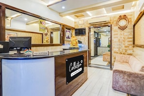 A reception desk with a 'Reception' sign, a 'Check Out Time 12 NOON' sign, and a 'No Outside Food Allowed' sign. - Super Collection O Sindhi Camp (Jaipur)