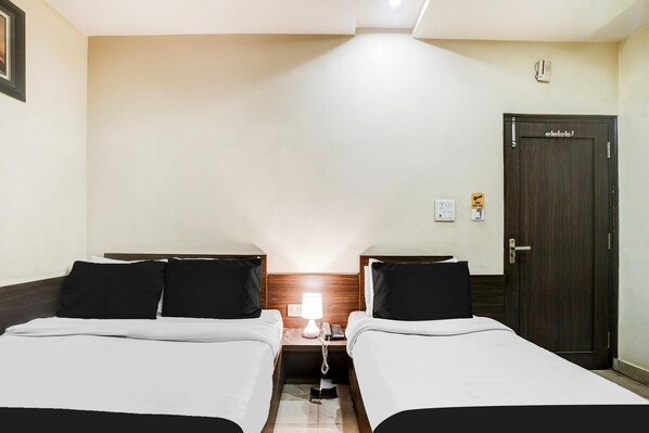 Habitación de hotel con dos camas, una mesita de noche con lámpara, un teléfono y una puerta con lector de tarjeta.