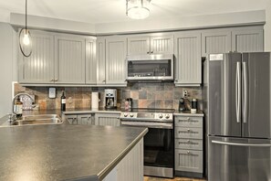 Una cocina moderna con gabinetes grises, electrodomésticos de acero inoxidable y una isla grande.