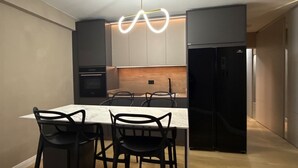 Ett modernt kök med en bänkskiva i marmor, svarta stolar och en unik lampa.