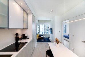 Une cuisine moderne dotée d’un îlot central, un coin repas avec une table et des chaises, et un espace de vie comprenant un canapé et un téléviseur.