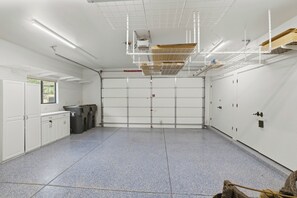 A clean, empty garage with a closed garage door, white walls, and a tiled floor. - NEW- Juniper Sky House: Rooftop Deck + Luxury (Sedona)