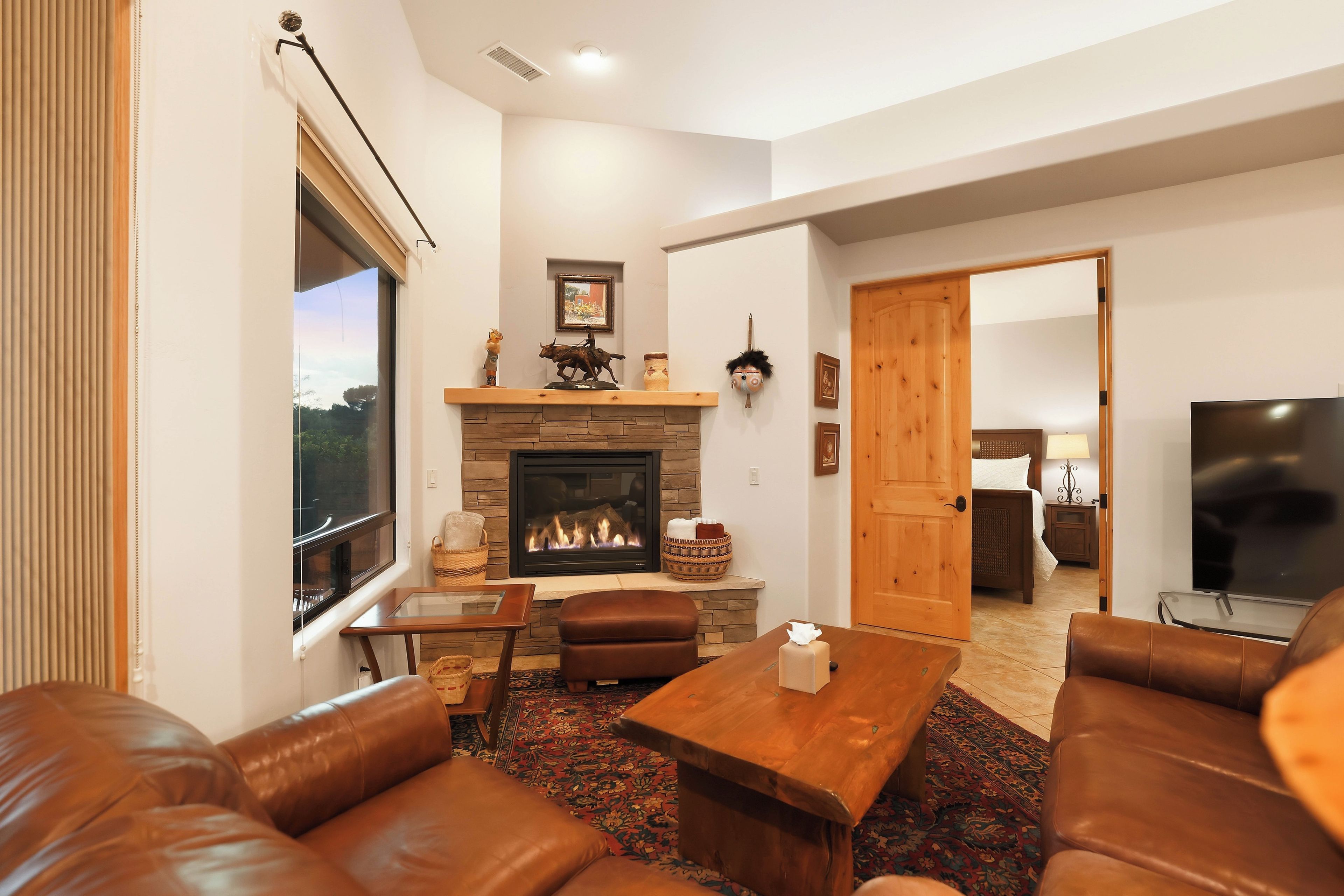 A living room with a fireplace, leather sofas, a coffee table, and a television.
