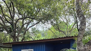 A small blue building with a single window and a door, surrounded by greenery and a concrete pathway. - Hotel y Centro Turístico Valle Encantado (Gracias)