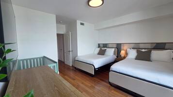 Une chambre d’hôtel avec deux lits, une table en bois et vue sur le couloir.