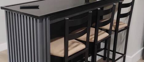 A modern kitchen with a black countertop, four chairs, and a welcome sign.