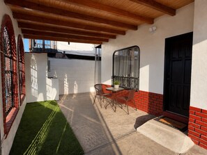 Varanda coberta com mesa, cadeiras, uma porta e janela com vista.