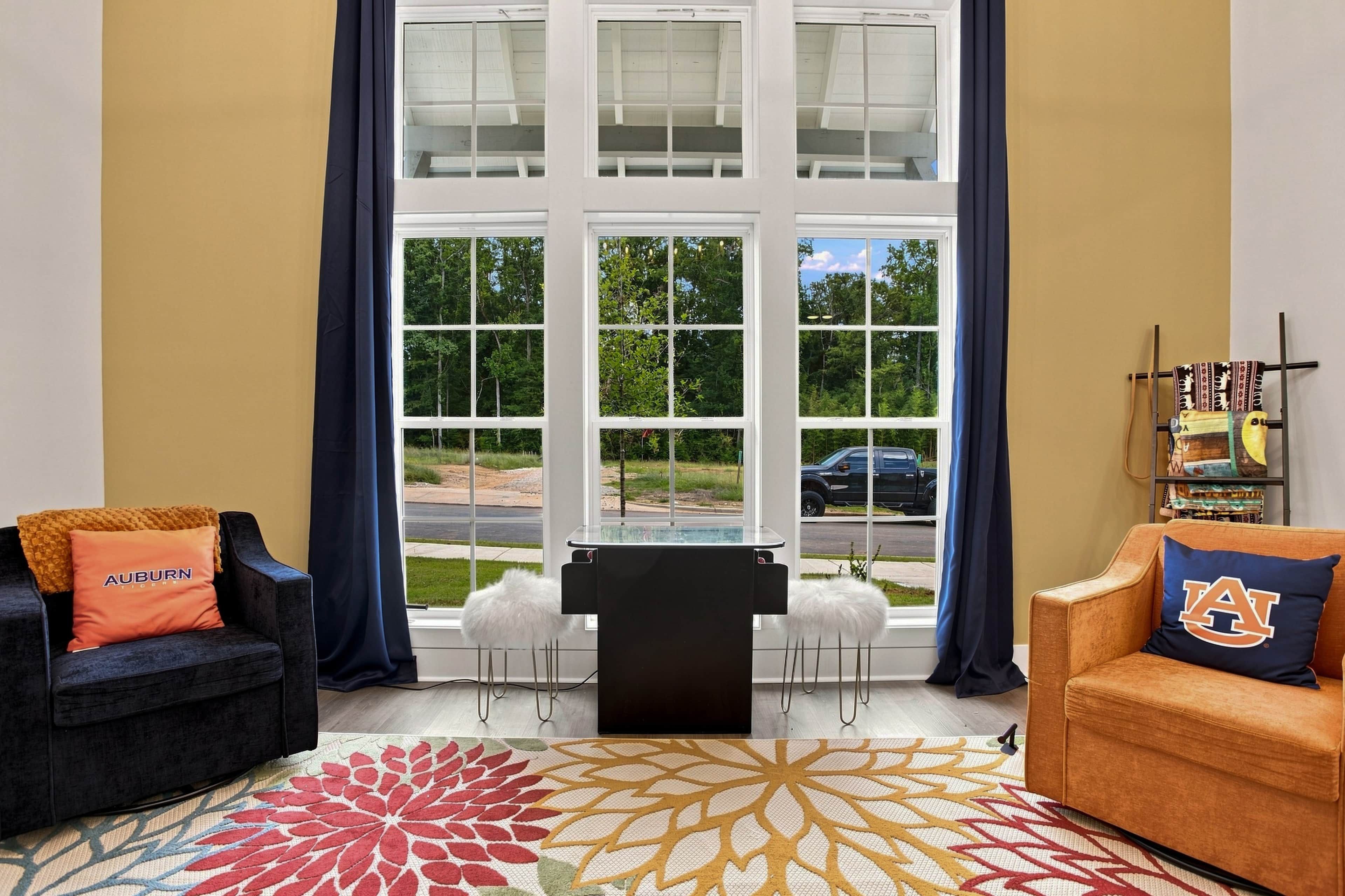 Ein Wohnzimmer mit großem Fenster, zwei Sofas, einem Couchtisch und einem gemusterten Teppich.